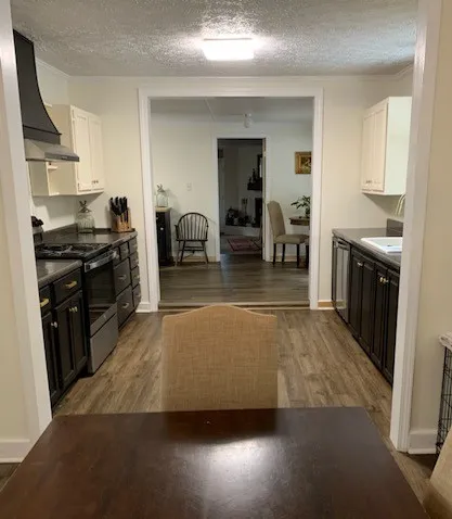 a living room with stainless steel appliances furniture stove top oven and cabinets