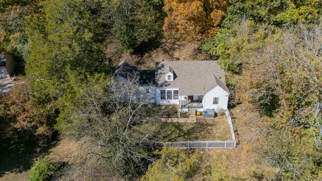 an aerial view of a house with a yard and large tree