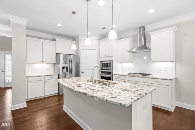 a kitchen with kitchen island a stove a sink a refrigerator and chairs