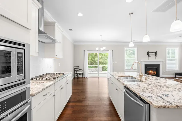 a large kitchen with cabinets counter top space a stove a sink and living room view