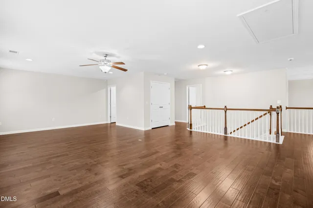 a view of an empty room with wooden floor and white walls