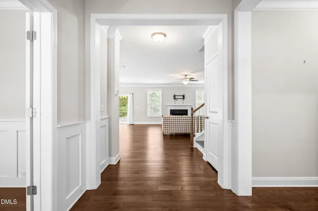 a view of a hallway with wooden floor kitchen and living room