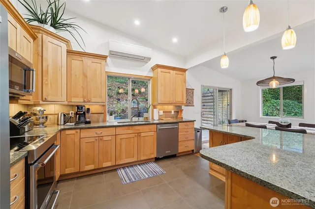 a large kitchen with stainless steel appliances granite countertop a stove top oven a sink dishwasher a dining table and chairs with wooden floor