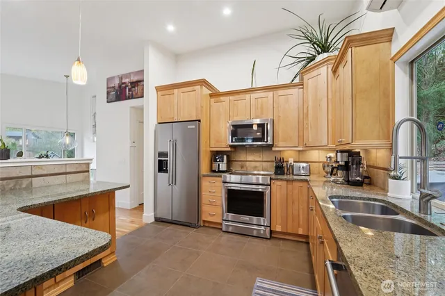 a kitchen with stainless steel appliances granite countertop a refrigerator a stove and white cabinets with wooden floor