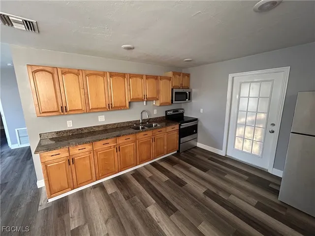 a kitchen with stainless steel appliances granite countertop a sink a stove cabinets counter space and a window