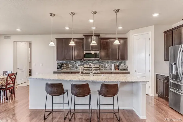 a kitchen with stainless steel appliances kitchen island granite countertop a kitchen island and chairs in it