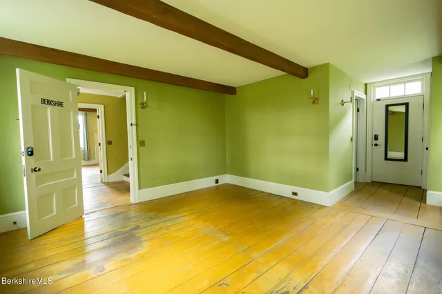 a view of an empty room with wooden floor and a bathroom