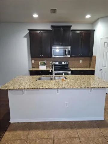 a kitchen with stainless steel appliances granite countertop a sink a stove a microwave and cabinets