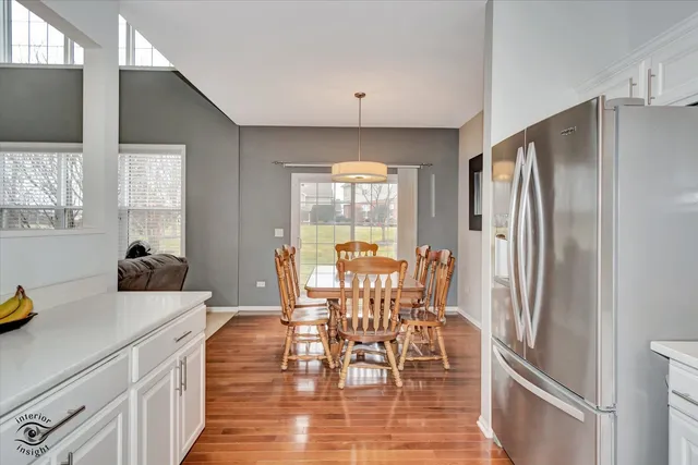 a kitchen with stainless steel appliances a dining table chairs stove refrigerator and cabinets