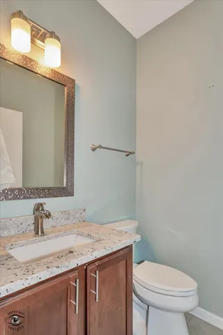 a bathroom with a granite countertop sink a toilet and mirror