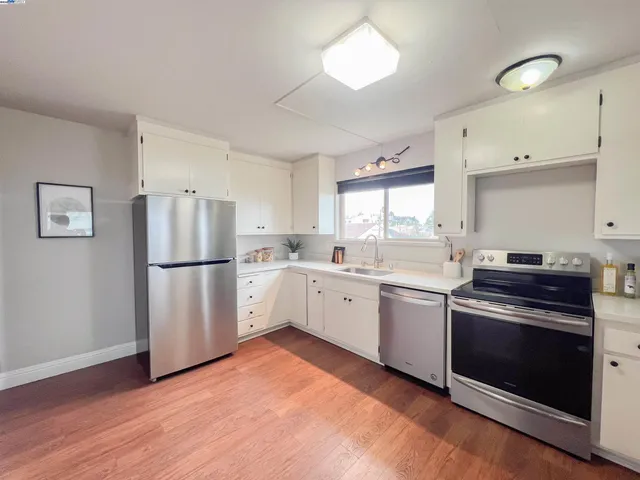 a kitchen with white cabinets white appliances and sink