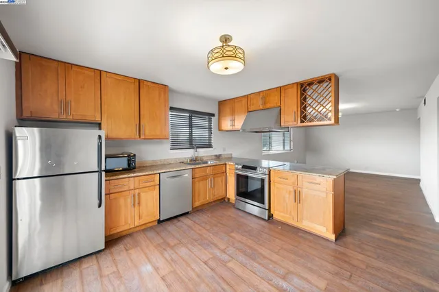 a view of an empty room with window and wooden floor