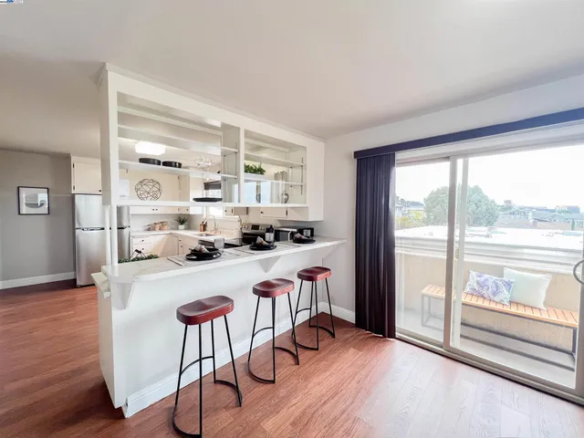 a kitchen with a refrigerator stove and wooden floor