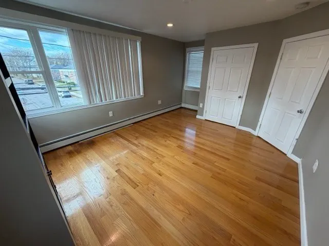a view of empty room with wooden floor and fan