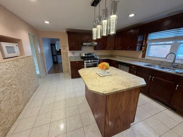 a kitchen with kitchen island granite countertop a sink a counter top space appliances and cabinets