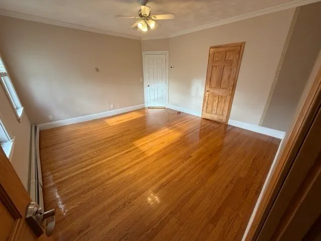 en empty room with wooden floor and fan
