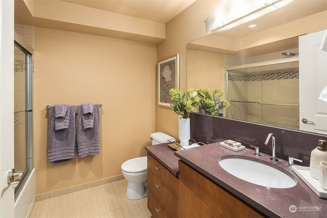 a bathroom with a granite countertop sink vanity mirror and toilet