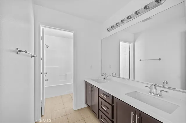 a spacious bathroom with a double vanity sink a mirror and a bathtub