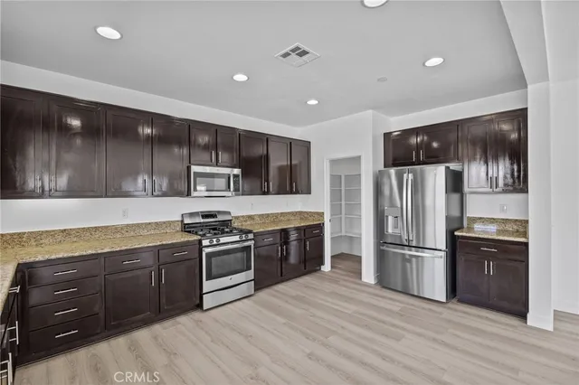 a kitchen with stainless steel appliances granite countertop a refrigerator and a stove top oven