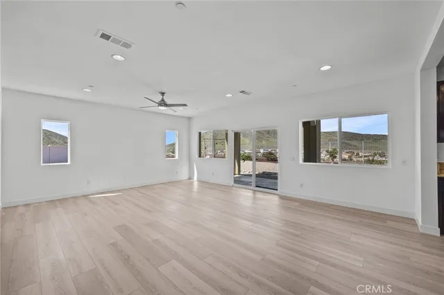 a view of an empty room with window and wooden floor