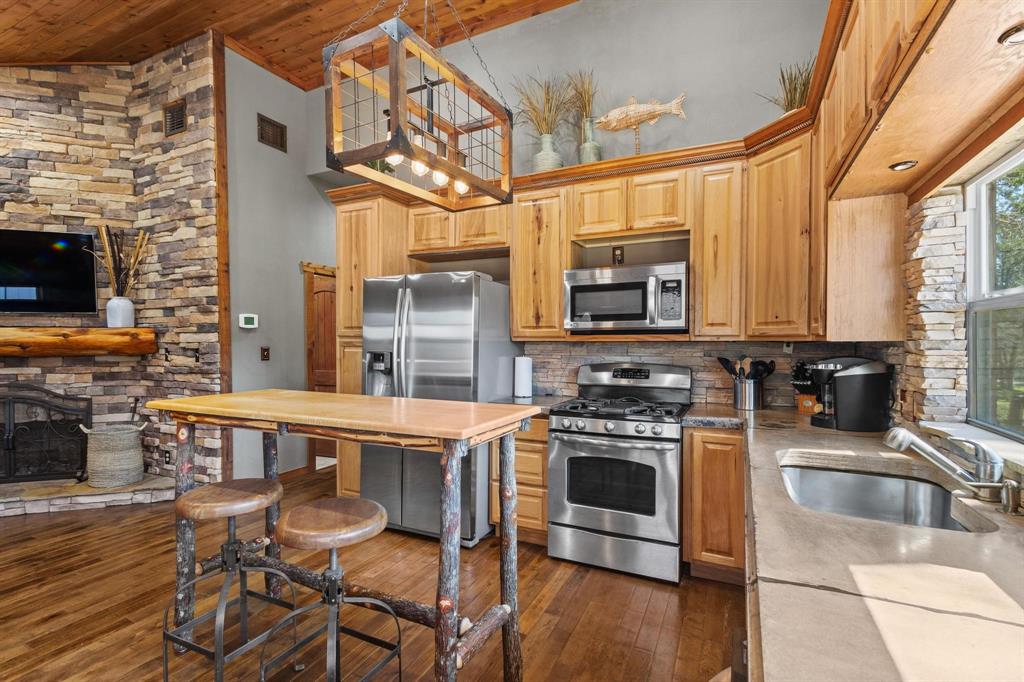 236 Homesite Road Pottsboro, TX 75076 - Photo 23 of 40 a kitchen with stainless steel appliances a stove a sink dishwasher and a microwave oven with wooden floor