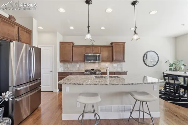 a kitchen with stainless steel appliances granite countertop a sink refrigerator and cabinets