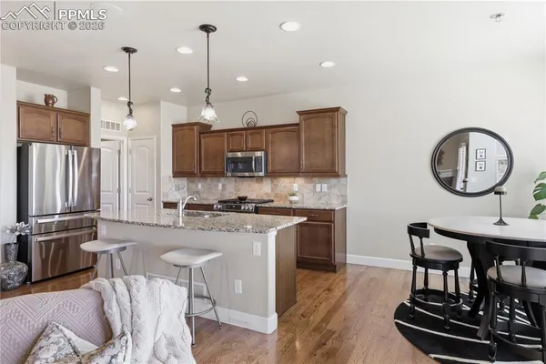a kitchen with kitchen island granite countertop a stove a sink a dining table and chairs