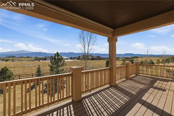 a view of a balcony with wooden floor next to a yard