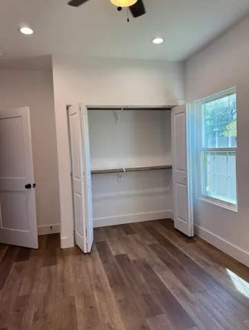 an empty room with wooden floor closet and windows