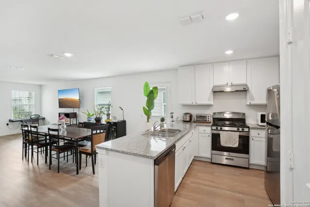a kitchen with appliances a sink a counter top space and living room view