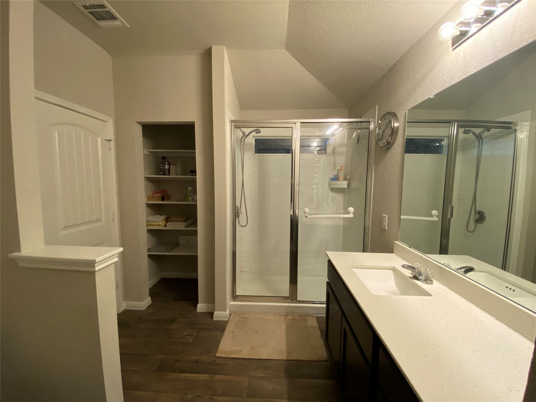 10916 Defender Trail Austin, TX 78754 - Photo 10 of 12 Full bath featuring vanity, a shower stall, dark wood-style floors, vaulted ceiling, and a walk in closet