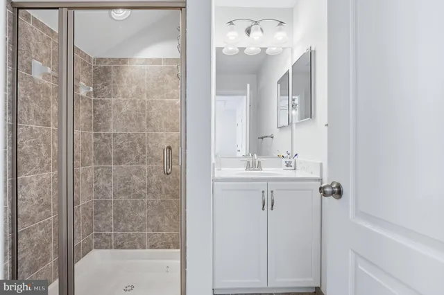 a bathroom with a shower a sink mirror and toilet