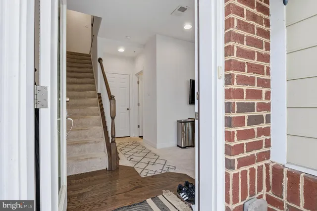 a view of a hallway with wooden floor and a bathroom