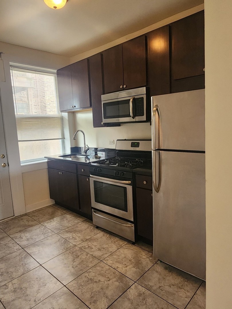 3219 West Division Street, Unit 2N Chicago, IL 60651 - Photo 5 of 14 a kitchen with granite countertop a refrigerator and a stove top oven
