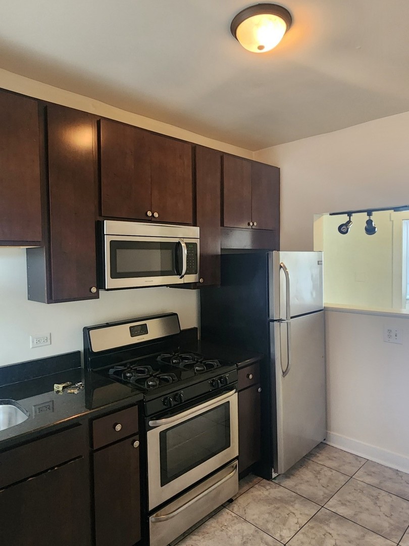 3219 West Division Street, Unit 2N Chicago, IL 60651 - Photo 6 of 14 a kitchen with stainless steel appliances granite countertop a refrigerator and a sink