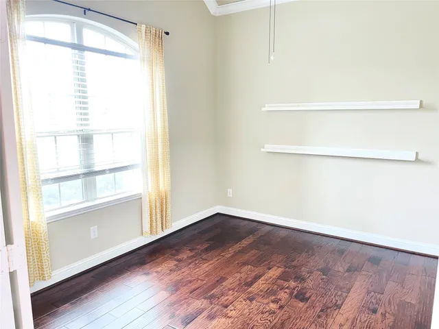 a view of an empty room with a window and wooden floor