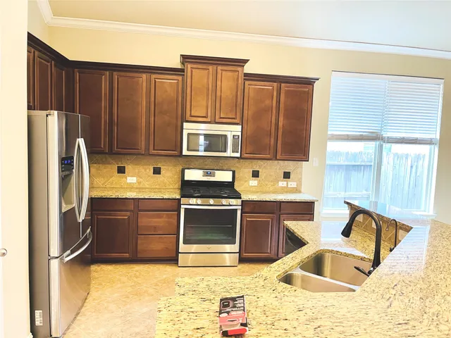 a kitchen with stainless steel appliances granite countertop a refrigerator sink and stove