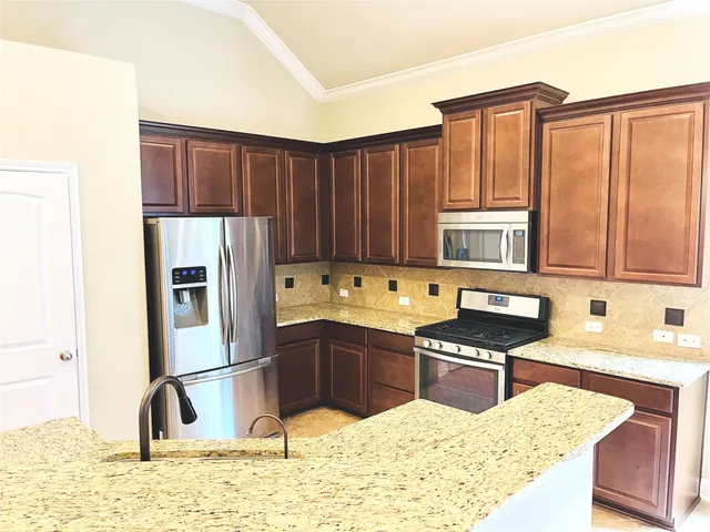 a kitchen with stainless steel appliances granite countertop a refrigerator a sink and a stove