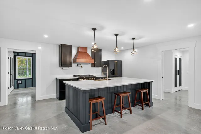 a kitchen with a stove a refrigerator a sink a dining table and chairs with wooden floor