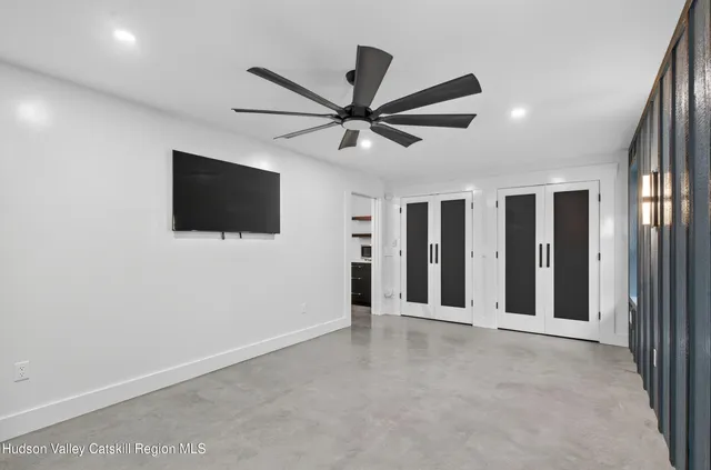 a view of a livingroom with a flat screen tv ceiling fan and window