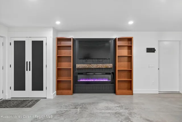 an empty room with wooden floor and way to kitchen