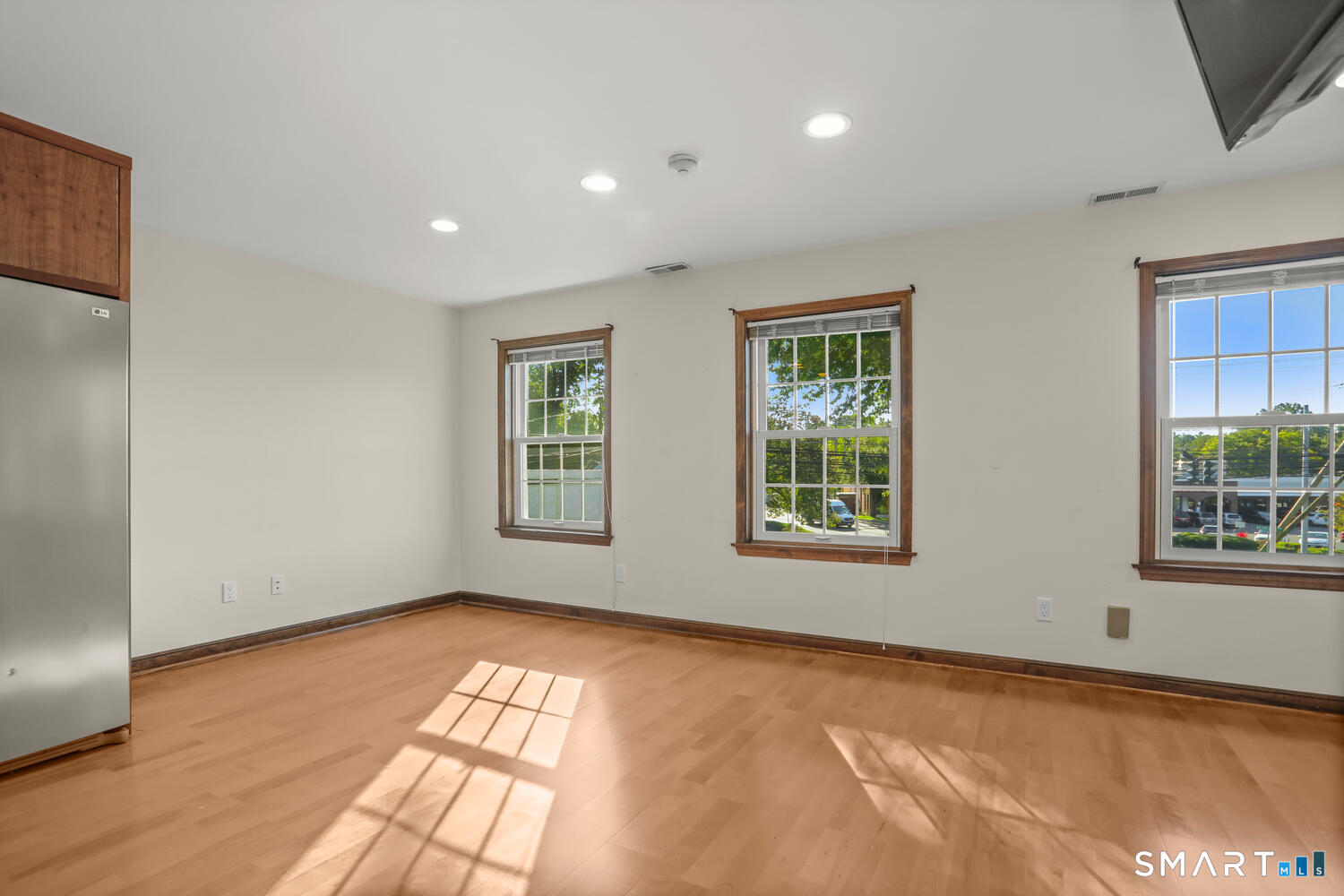 a view of an empty room with a window and wooden floor