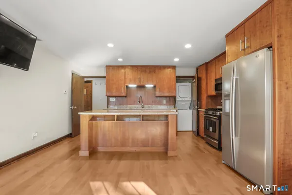 a kitchen with stainless steel appliances granite countertop a refrigerator a stove and a sink