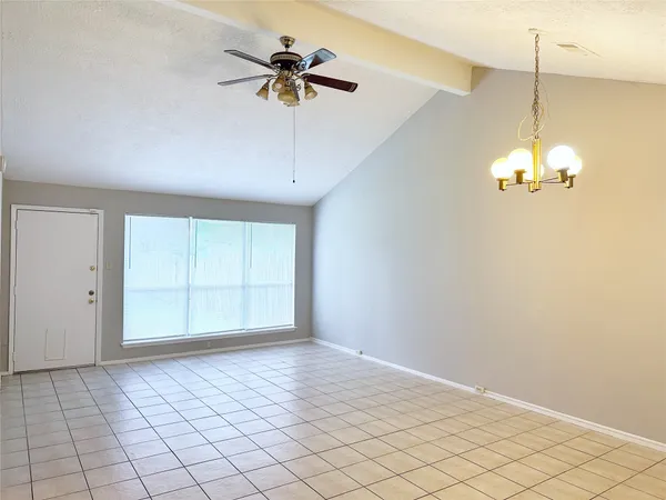 an empty room with chandelier fan and windows