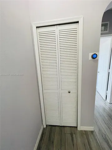 a view of a hallway with wooden floor and closet