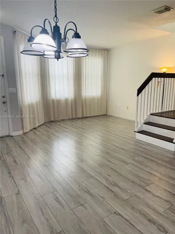 an empty room with wooden floor wooden door and windows