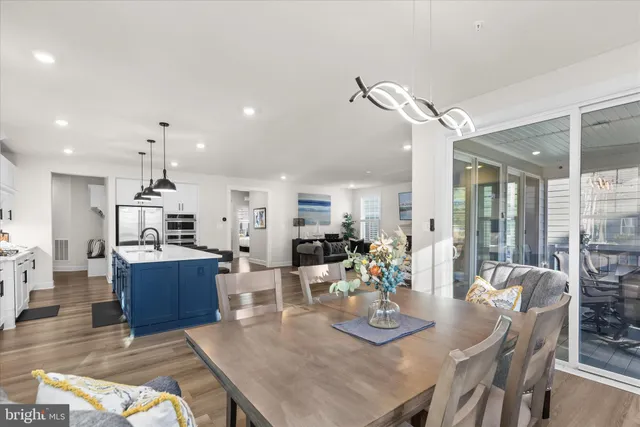 a kitchen with stainless steel appliances kitchen island granite countertop a table chairs sink and cabinets