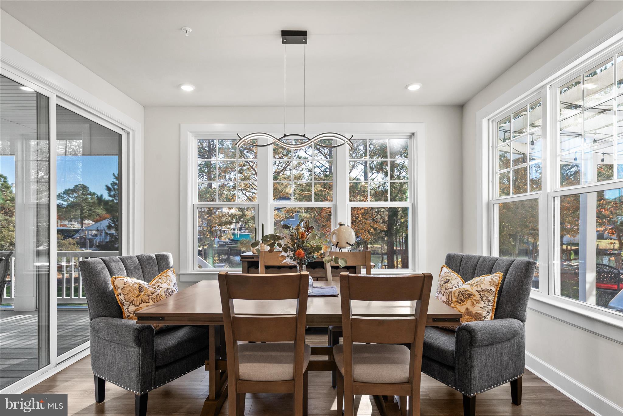12377 Hidden Bay Drive Berlin, MD 21811 - Photo 17 of 71 a dining room with wooden floor a chandelier a glass table and chairs