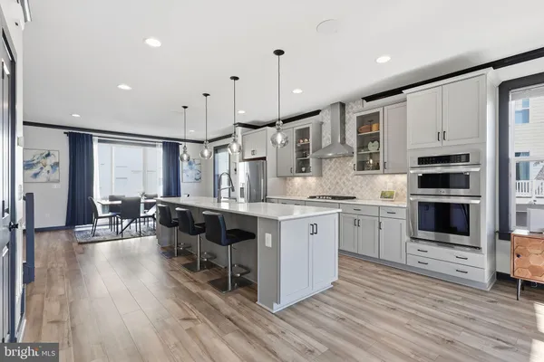 a kitchen with stainless steel appliances kitchen island granite countertop a stove a sink a refrigerator and white cabinets with wooden floor