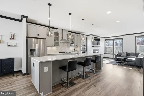 a open kitchen with stainless steel appliances granite countertop a stove a refrigerator a kitchen island a dining table and chairs with wooden floor